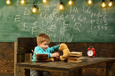 Okul kafeteryasında. Küçük çocuk okul kafeteryasında. Sağlıklı beslenme için okul kafeteryasında. Çocuk oyuncak ayı oyuncak okul kafeteryasında besleme. Bilgi lezzetlidir