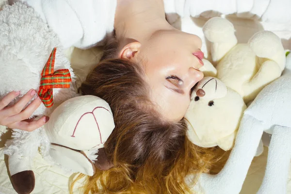 ベッドで寝ている巻き毛を持つ美しい少女。かなり若い女性の睡眠グッズを抱き締めます。いい夢、見てね — ストック写真