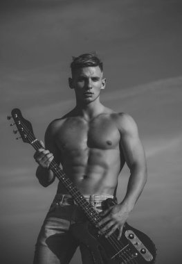 Müzikal yıldızı. Maço kas gövde ile oynamak elektro gitar üzerinde mavi gökyüzü