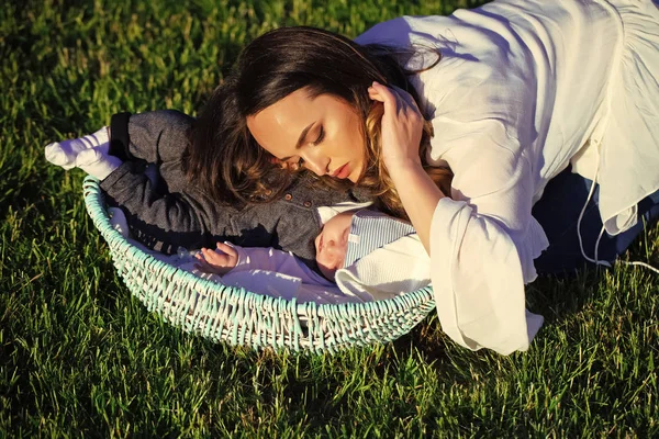 Maternidad. Mujer dormir con bebé niño niño en cesta al aire libre —  Fotos de Stock
