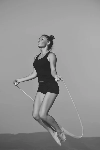縄跳びの縄で練習。青い空を背景に少女のトレーニング. — ストック写真