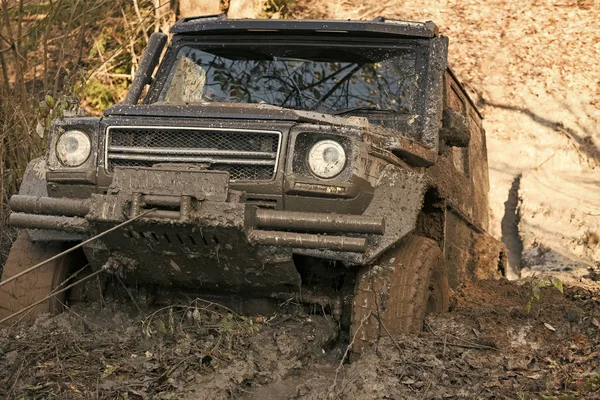 Competition of off-road cars. SUV is pulled out from puddle of mud by car winch. — Stock Photo, Image
