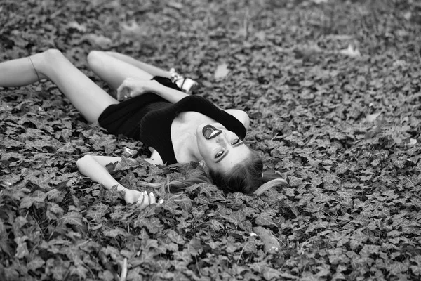 Jonge prostituee. Lachende meisje liggend op groene bladeren — Stockfoto