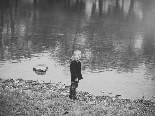 Enfant seul. petit garçon en automne écharpe et manteau à l'eau de la rivière — Photo