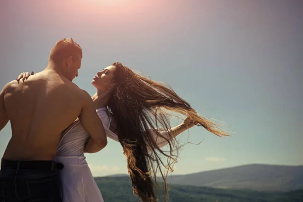 Le donne adorano. Uomo abbraccio donna con i capelli lunghi volanti nella giornata di sole — Foto Stock