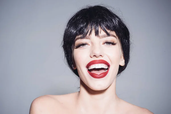 Girl on happy smiling face posing with naked shoulders. Lady in black wig with make up on grey background. Beautiful smile concept. Woman with attractive red lips looks at camera — Stock Photo, Image