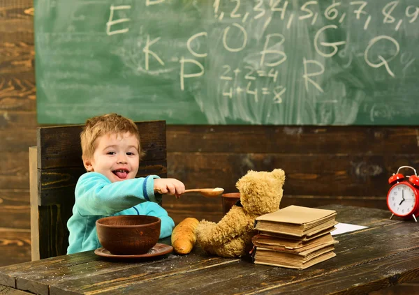 Almuerzo saludable en la cafetería de la escuela. El niño pequeño comparte el almuerzo saludable con un amigo de juguete. Chico disfrutar de un almuerzo saludable con oso de peluche. Comida saludable para el almuerzo. No basura, conoce la salud. — Foto de Stock