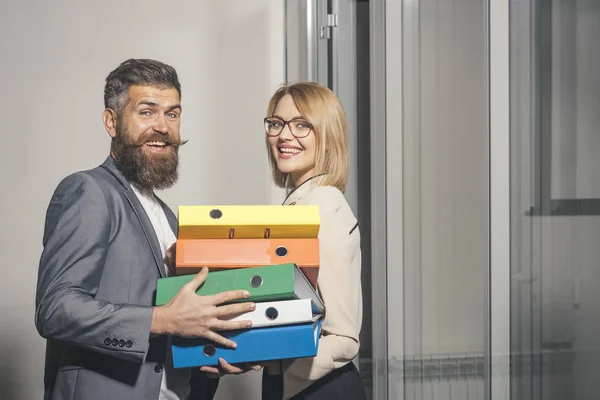 Un homme d'affaires aide une femme d'affaires à porter des classeurs au bureau. Coopération entre entreprises et travail d'équipe — Photo