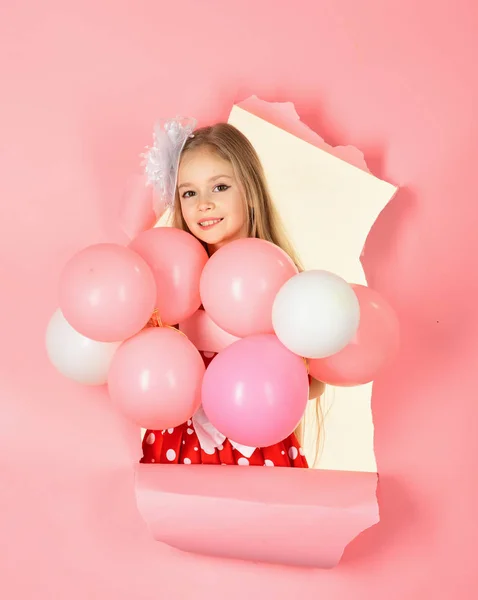 Kleines Mädchen im Partykleid blickt mit rosa Luftballon in die Kamera. — Stockfoto