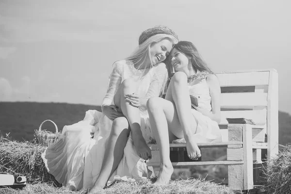 Girlfriends rest. Two girls sitting on bench on hay — Stock Photo, Image