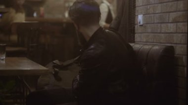 Genç işadamı kafede telefonda konuşuyor.