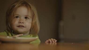 Komik çocuk sütlü yulaf lapası yiyor. Küçük adam yulaf lapasının tadını çıkarıyor.