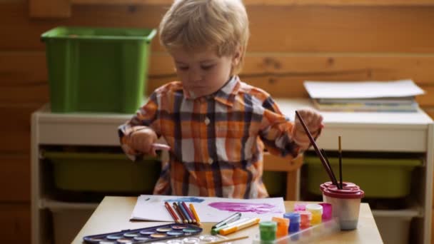 Ребенок рисует картину с paitint в альбоме, используя много инструментов живописи. Концепция творчества — стоковое видео