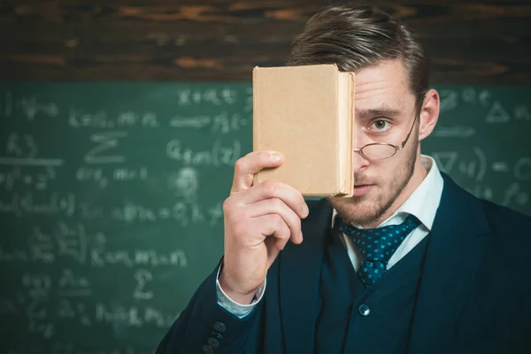 Devias lembrar-te. Professor desgaste formal e óculos parece inteligente, fundo quadro. Homem sem barba segura livro na frente da cara. O professor insiste na necessidade de memorizar informações. Conceito de educação — Fotografia de Stock