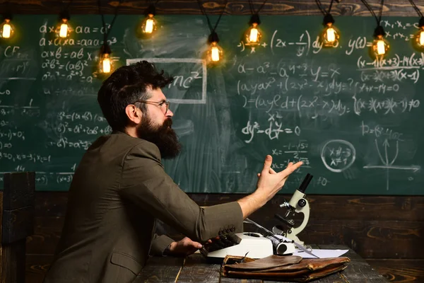 Mann sitzt mit Büchern am Tisch und schreibt. Wissenschaftler, Lehrer und Student. Hausaufgaben oder Unterricht auf der Tafel Hintergrund — Stockfoto