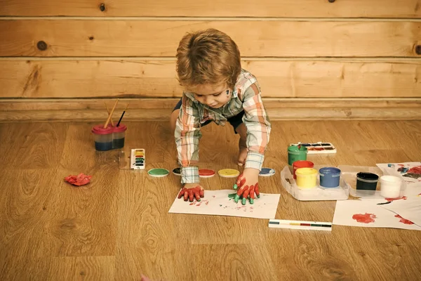 Молодой художник. Мальчик-художник рисует отпечатки рук окрашенными краской руками — стоковое фото