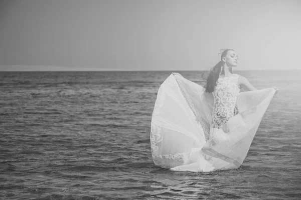 Honeymoon trip. Bride on sunny summer day on blue water