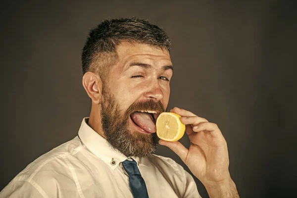 vitamin c. man with long beard lick lemon fruit on black background