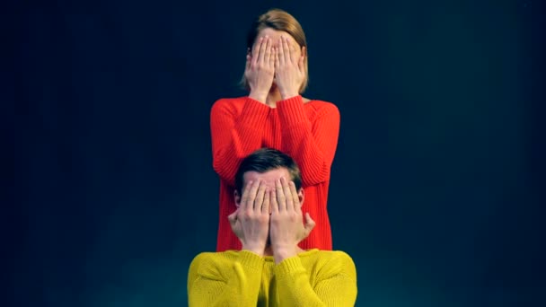 Un niño y una niña en suéteres de colores muestran diferentes emociones después de abrir sus rostros, que eran manos cerradas. Concepto de manifestación de emociones . — Vídeos de Stock
