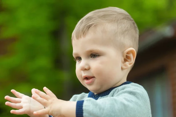 Bébé garçon avec visage mignon jouant sur fond naturel flou — Photo