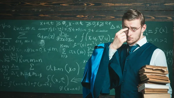 Lehrertracht und Brille sehen pfiffig aus, Kreidehintergrund. Der Mann am Ende der Stunde nimmt die Brille ab. Bekommen Sie eine Tafel voller mathematischer Formeln? Lehrer beendete Erklärung — Stockfoto