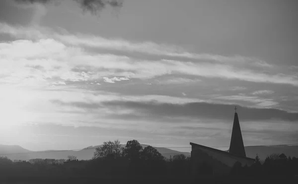 Vallás hit szerint. Táj és templom, kereszt sziluettje a felhős napnyugtakor ég — Stock Fotó