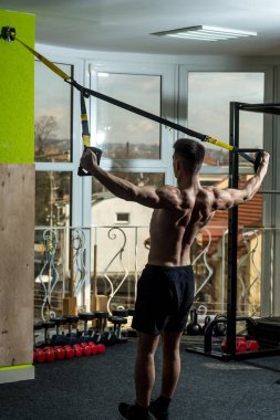 Spor ve spor salonu konsept. Gövde, sporcu, atlet, kas maço mu egzersiz trx döngüler ile pencere arka plan üzerinde olan adam. Adam çıplak gövde ve geri içinde jimnastik salonu kas eğitim, trx zevk