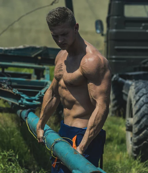 Bodybuilder concept. Bodybuilder man pull truck trailer. Handsome bodybuilder with six pack and ab on muscular torso. Strong bodybuilder on construction site — Stock Photo, Image