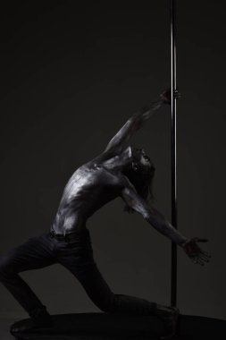 Metal yüzey ile seksi maço. Atletik erkekleri pilon üzerinde akrobatik öğeleri gösteriyor. Pole dans spor. Pilon üzerinde dans gümüş gövde sanat kaslı adam. Onun hedefi için hareket. kutup dans egzersiz. Özgürlük
