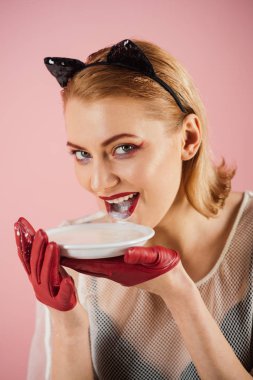 Ekoloji ürün ve heath. Kız yavru kedi kulakları ve yoğurt pembe bir arka plan üzerinde kırmızı eldivenler. Kedi kadın ye ekşi krema. Seksi kedi kadın yalamak süt plaka. Yiyecek ve içecek. Diyet ve sağlık.