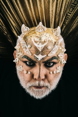 İblis kafası boynuzları, korku ve kabus kavramı. Karanlıktan görünen altın kanatlı vampir. Dikenler yüz siyah arka plan üzerine ile kötü canavar