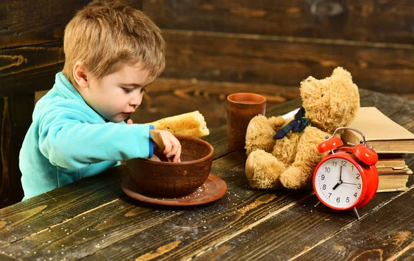 Los niños comen comida en la mesa de madera. Kid disfrutar de la comida con un amigo de juguete. Menú infantil. Niño comiendo. Eres lo que comes. — Foto de Stock