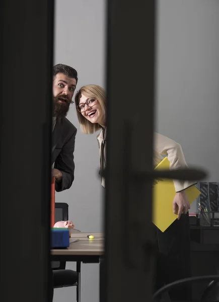 Porträtt av två leende medarbetare tittar på kameran. Kvinna med bindemedel och mannen med skägg står framför glasdörr — Stockfoto
