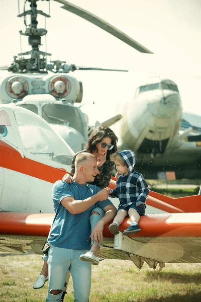 Travelling concept. Family at retro planes parked on ground, travelling. Child with mother and father visit air show while travelling. Travelling by plane. Lets fly away
