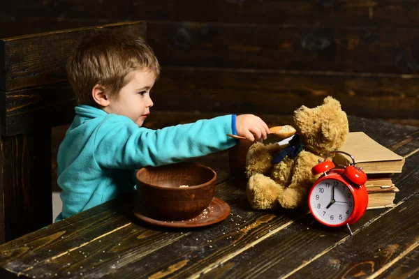 Friend and friendship. Little boy feed toy friend from spoon. Child have dinner with teddy bear friend. Best friend. Eat right with a healthy bite