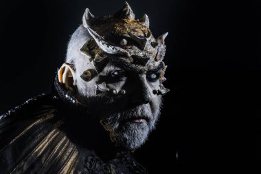 Şeytan siyah zemin üzerine altın yakalı. Adam dikenler veya siğiller ile yüz pırıltılar ile kaplı. Beyaz sakallı komuta sizde canavar gibi giyinmiş. Fantezi kavramı. Uzaylı, iblis, büyücü makyaj.