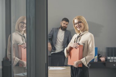 Anlaşma önce evrak. Mutlu kadın ve office arka planda sakallı adam. Dosya klasörleri iş kadın gülümse. En iyi koşullar ile sözleşme. Kendinden emin ve başarılı iş arkadaşları