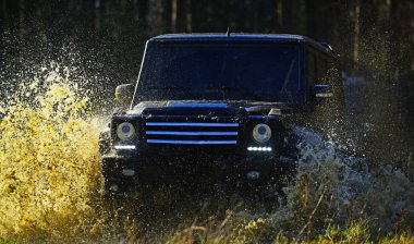 Sonbahar ormanda yarış araba. Aşırı, meydan okuma ve 4 x 4 araç konsepti. SUV veya offroad araba yolda su birikintisi su sıçrama ile geçiş çim kaplı. Offroad yarış Sonbahar Doğa arka plan üzerinde