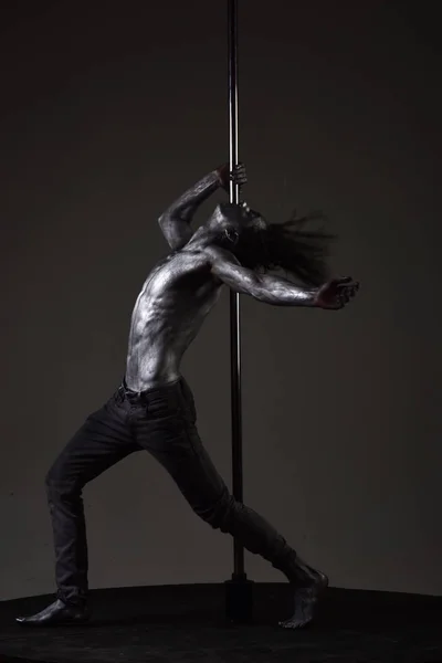 Forte exercício dançarino no pólo. Liberdade. Machão sexy com pele de metal. Homem atlético faz elementos acrobáticos em pilão. Homem musculoso com arte corporal prateada dançando em pilão. Polo esporte de dança — Fotografia de Stock