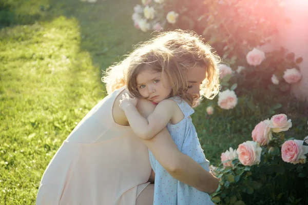 Kvinna med flicka barn på blommande ros blommor — Stockfoto