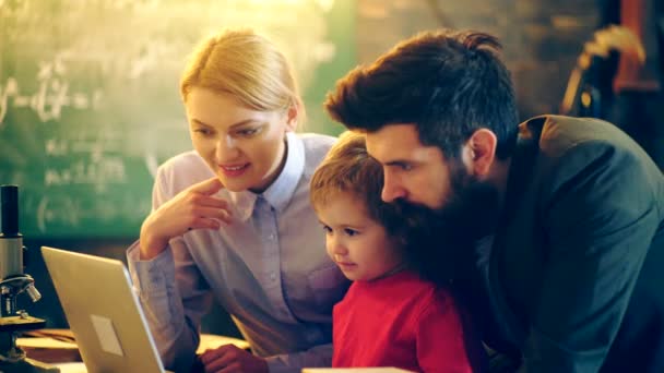 Two adults and a boy watching a movie on a laptop. Concept of the educational process. Teacher in classroom. Teacher and student. Back to school. — Stock Video