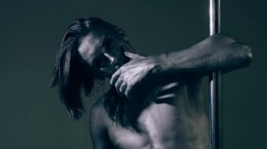 Moda kavramı. Bir adam bir gri gövde ile bir pilon üzerinde güvenerek teşkil etmektedir. Adam kendine güvenen seksi ifade ile poz tutan parmak dudaklarından.