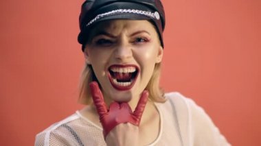 Heavy metal kız kırmızı bir arka plan üzerinde kükrüyor. Moda kavramı. Kırmızı zemin üzerine izole.