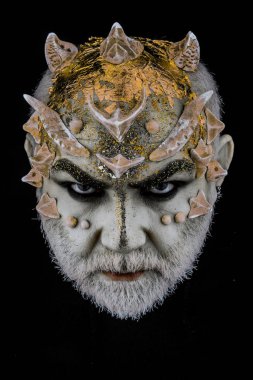 Dikenler veya siğiller, baş yüz pırıltılar ile kaplı, yakın çekim. Ciddi yüz, siyah zemin üzerine iblis. Uzaylı, iblis büyücü makyaj. Fantezi kavramı. Sakallı canavar makyaj ile üst düzey adam.