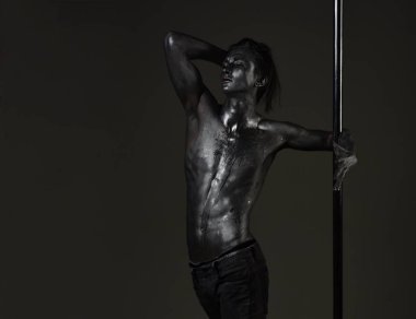 Pilon üzerinde dans gümüş gövde sanat kaslı adam. Atletik erkekleri pilon üzerinde akrobatik öğeleri gösteriyor. Pole dans spor. Metal yüzey ile seksi maço. Güçlü dansçı egzersiz kutup. Özgürlük.