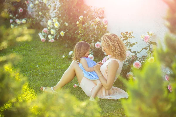 Mulher com menina criança em flores de rosa florescentes — Fotografia de Stock
