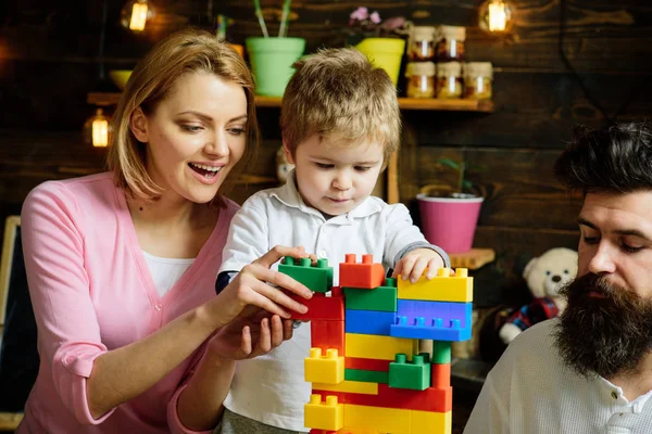 Concepto de juguete. Juguete educativo para niños. Niño pequeño juega con ladrillos de juguete. Hijo con madre y padre construyen estructura con juguete conjunto de construcción — Foto de Stock