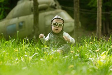 Çocuk pilot kask ve yeşil çim oturan gözlük