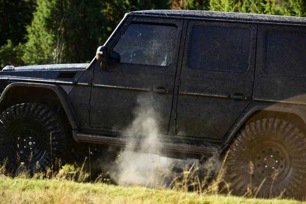 Veicolo coperto di gocce di fango. Lato dell'auto coperto di sporcizia e nuvola di fumo. Off road racing, forza e concetto di intrattenimento estremo. SUV sullo sfondo della natura — Foto Stock