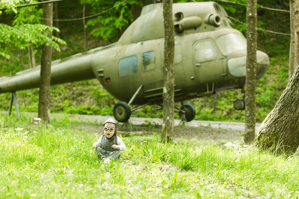 Pojke i pilot hjälm och glasögon som sitter i gröngräset — Stockfoto